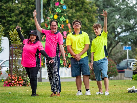 Image shows four people celebrating on grass