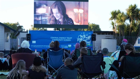 Families watching an outdoor film in a park.