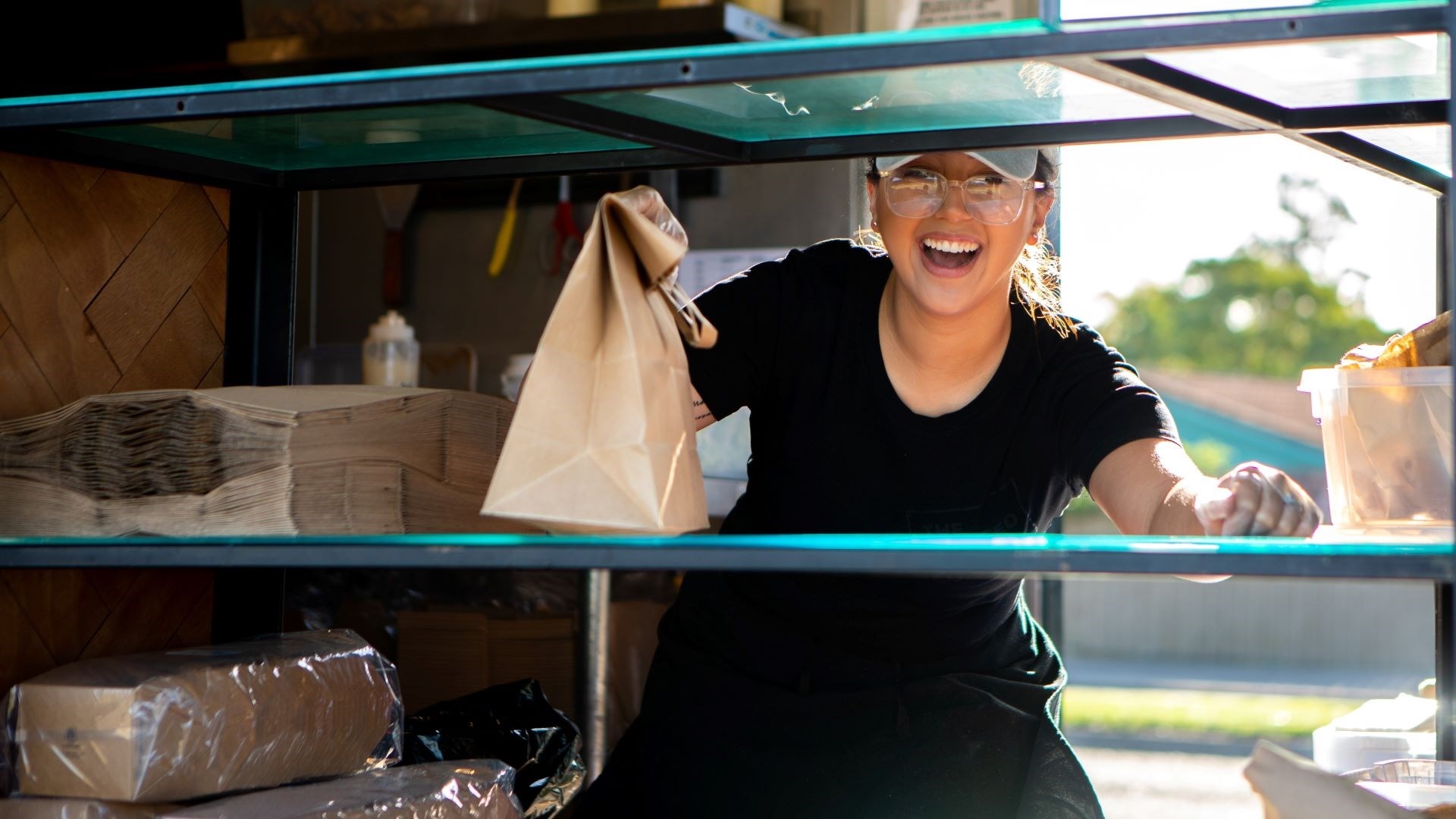 A smiling food truck vendor hands over the goods.