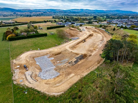 Image shows aerial view of a attenuation pond under construction by residential area 