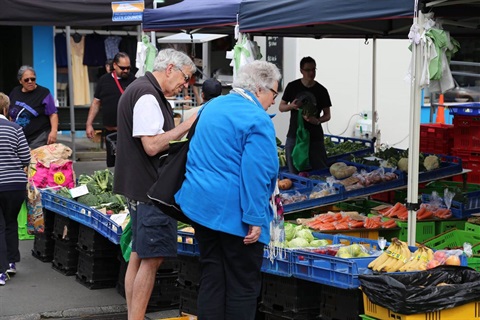 Couple buying fruit and veges at a market stall.