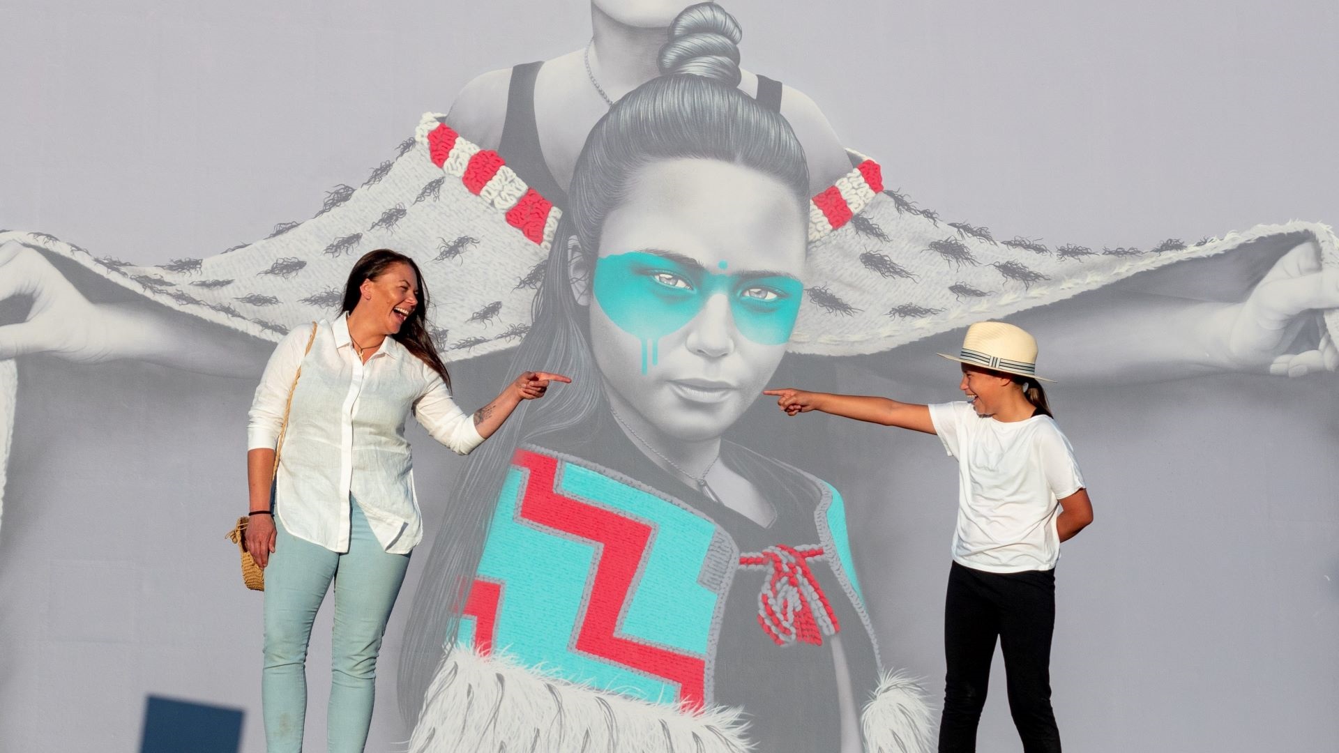 Woman and child pose in front of mural.