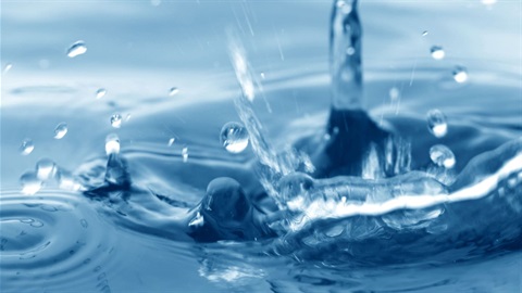 Extreme closeup of a drop of water splashing and forming ripples.