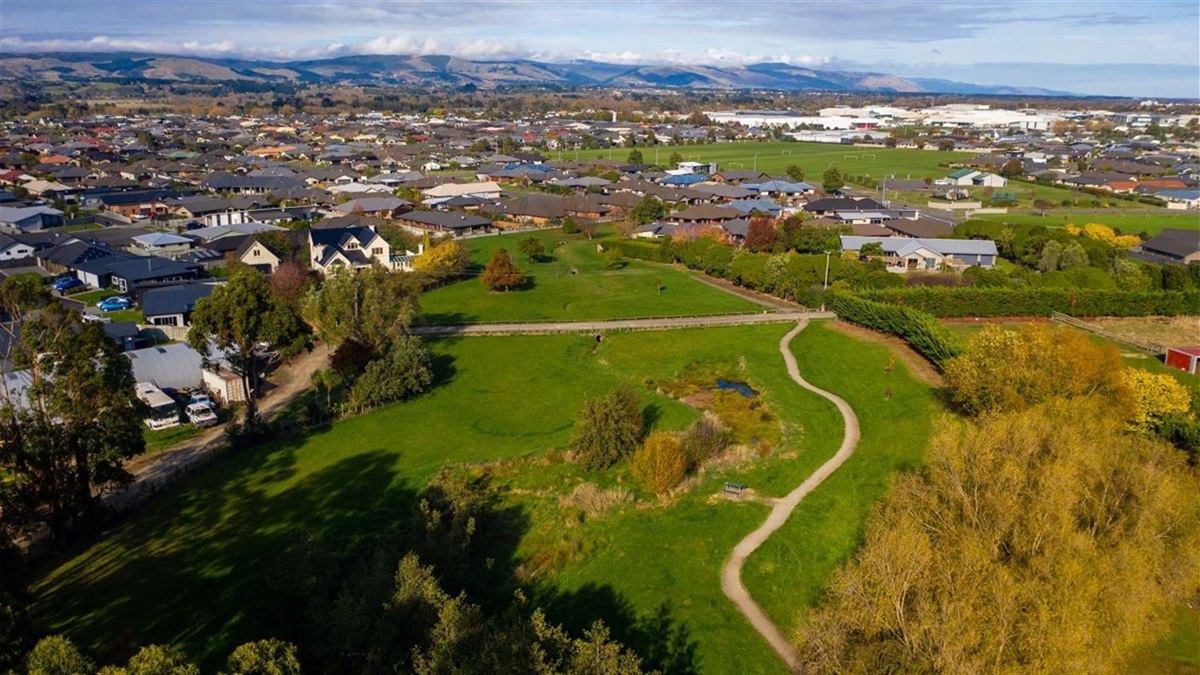 Aerial view of a limestone walkway winding along a hilltop. There are stands of trees nearby but not along the pathway.